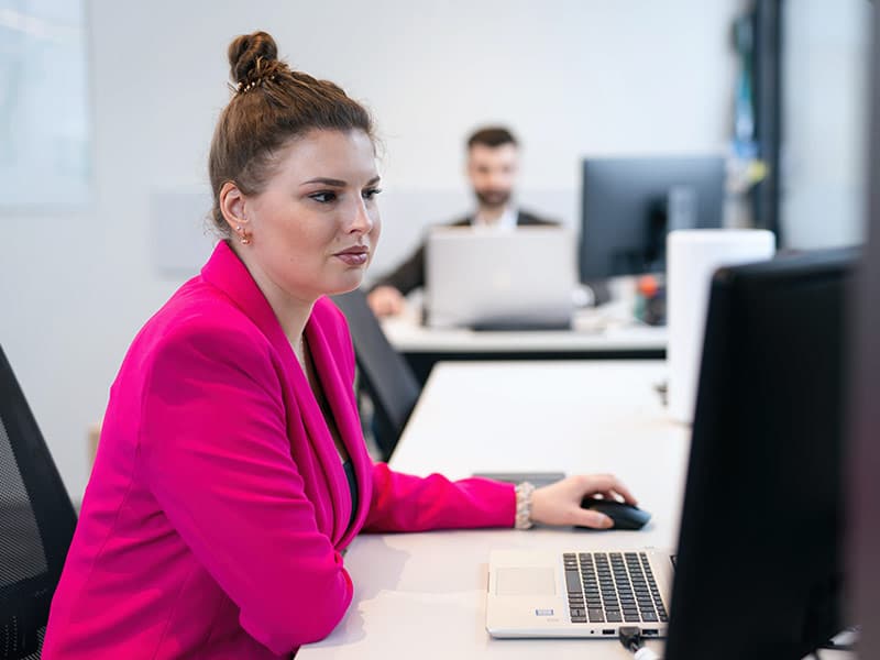 Lady in pink jacket working on a computer